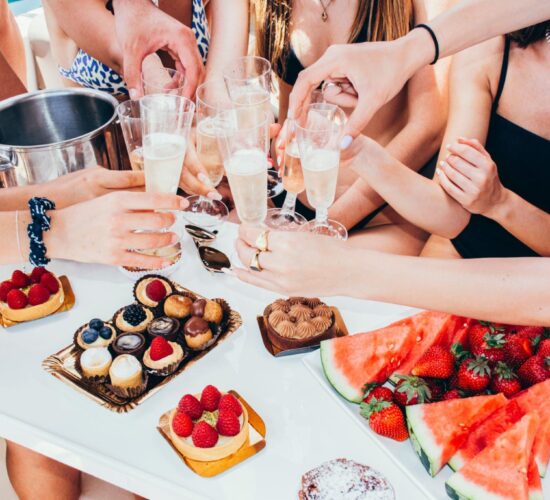 A cheerful group toasting with sparkling champagne over a table full of exquisite dessert options