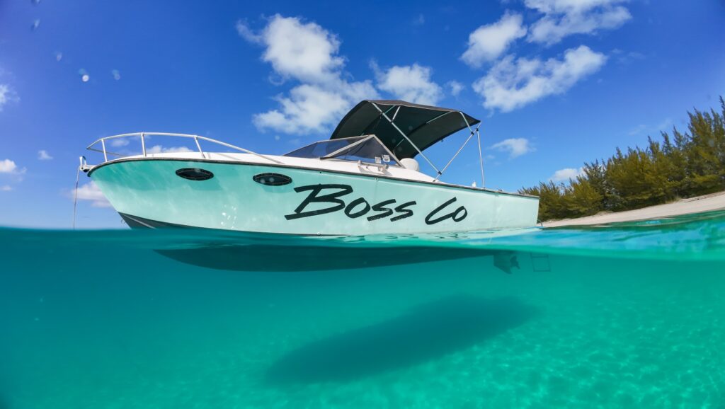 Private boat tour boat Boss Co anchored in clear turquoise water near Rose Island, Bahamas
