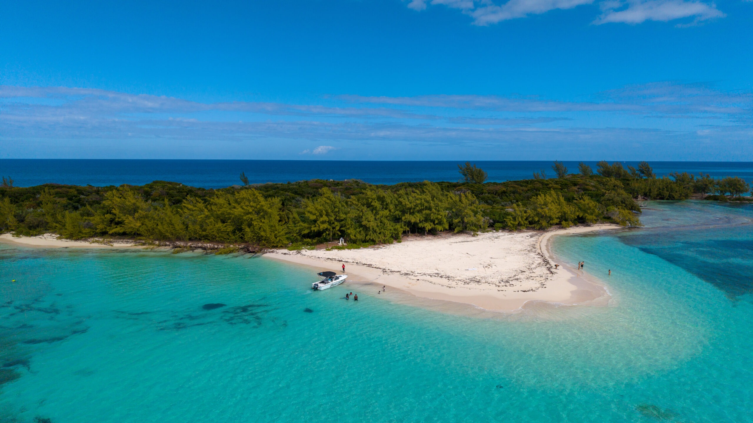 Aerial view of a private boat anchored at a secluded beach on Rose Island near Nassau, Bahamas with turquoise water and white sand shoreline.