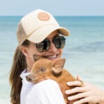 Swimming pigs Nassau guest holding piglet on Rose Island beach