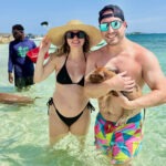Couple holding pig in the water during Bahamas swimming pigs experience