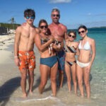 Guests feeding swimming pig in shallow water near Nassau Bahamas