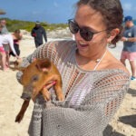 Swimming pigs Nassau guest holding piglet on Rose Island beach